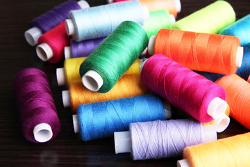 Multicolor sewing threads on wooden background