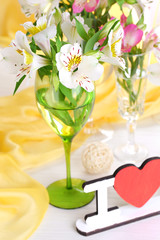 Freesias in glasses on table on fabric background