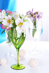 Freesias in glasses on table on fabric background