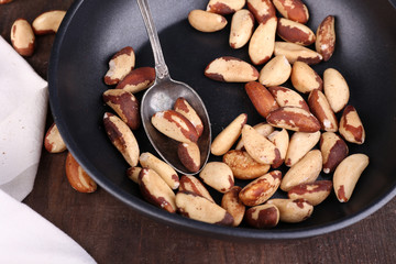 Tasty brasil nuts in pan on wooden background
