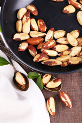 Tasty brasil nuts in pan on wooden background