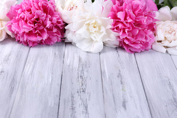 Beautiful pink and white peonies on color wooden background