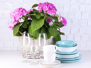Blooming hydrangea and utensils on table on grey wall