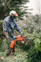 Obraz premium Professional gardener using chainsaw