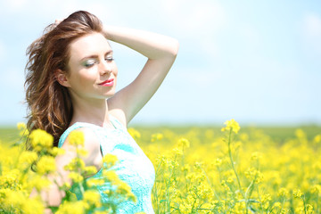 Naklejka na ściany i meble Beautiful young woman in flower field