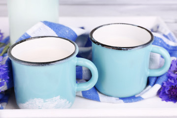 Cups of milk and cornflowers on wooden table