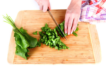 Female hand cutting greens on cutting board isolated on white