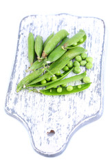 Fresh green peas on wooden board isolated on white background