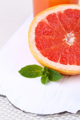 Half of grapefruit and spoon on wooden board on light