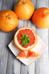 Ripe grapefruits on plate on color wooden background