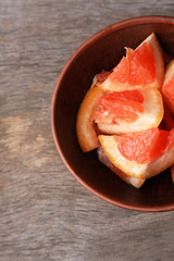 Ripe chopped grapefruit  in bowl, on wooden background