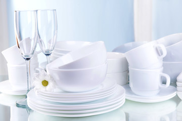 Set of white dishes on table on light background