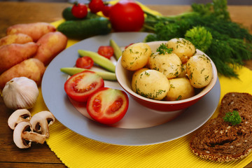 Young boiled potatoes with vegetables on table, close up