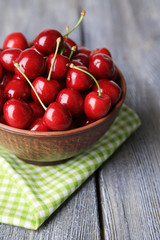 Sweet cherries in color bowl on wooden background