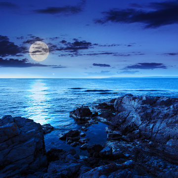 calm sea with boulders on coast at night
