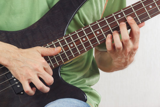 Hands of artist playing the electric bass guitar closeup