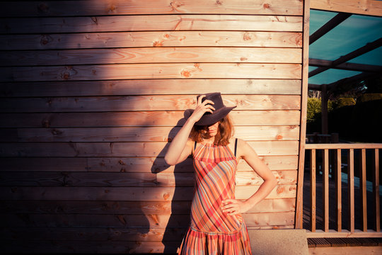 Young woman wearing cowboy hat by a cabin