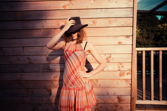 Young woman wearing cowboy hat by a cabin