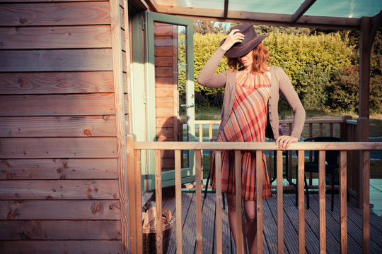Young woman with cowboy hat stading on the porch of cabin