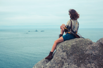 Young woman sitting on a rock by the sea