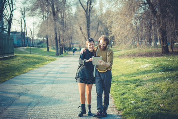 young modern stylish couple using tablet urban