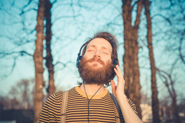 young bearded stylish handsome hipster man listening music