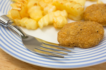 Chicken nuggets with french fries and fork on table