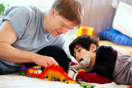 Handsome father playing cars with disabled son