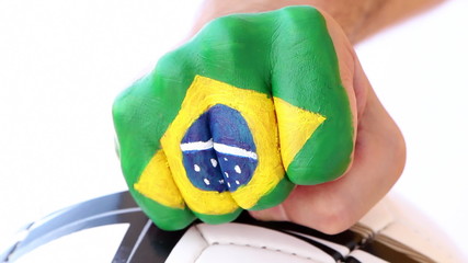 Male fist with brazilian flag on it hits football soccer ball - Powered by Adobe