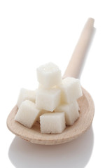 cubes of white sugar in a wooden spoon closeup