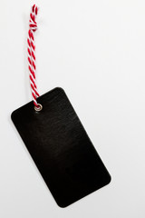 Schwarzer leicht glänzender Anhänger am rot weißen Band