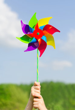 Child Hands Holding Pinwheel Against Blue Sky.