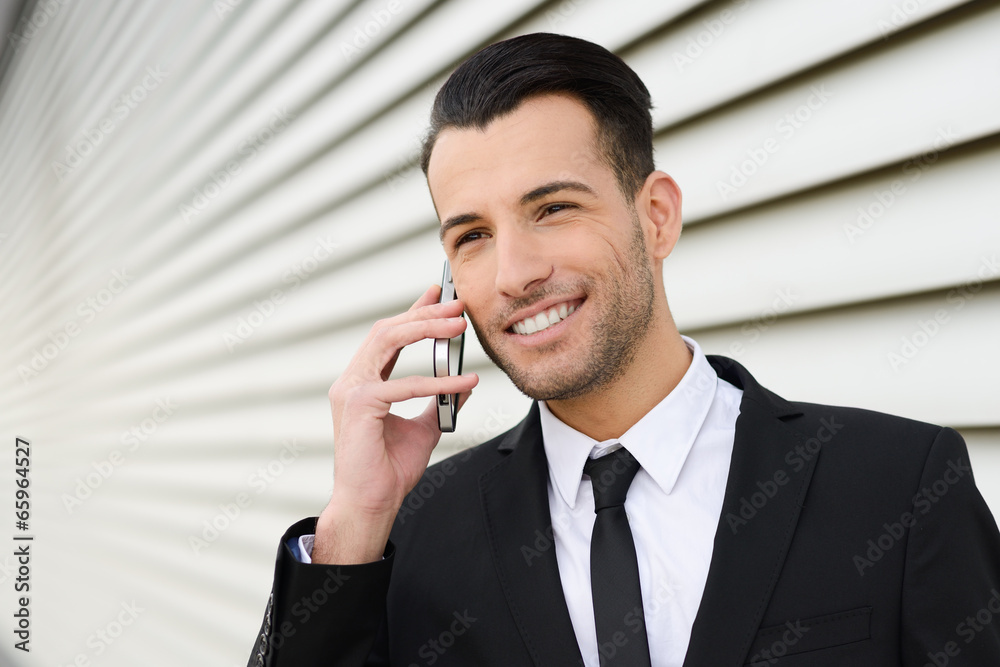 Wall mural Attractive young businessman on the phone in an office building