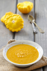 Pumpkin creamy soup in ceramic plate on wooden table