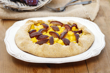 Pumpkin, plum and apricot galette on wooden table