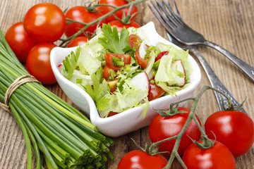 Bowl of fresh salad on rustic wooden table