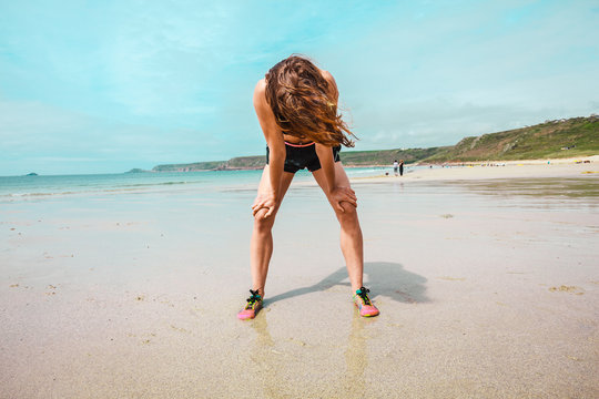 Athletic young woman resting after running on beach