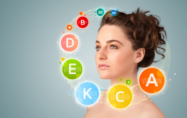 Pretty young girl with colorful vitamin icons and symbols