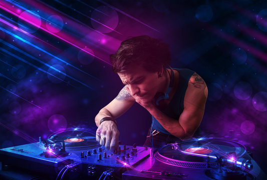 Young DJ playing on turntables with color light effects