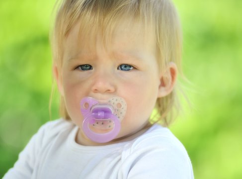 Cute baby with soother in his mouth, outdoors.
