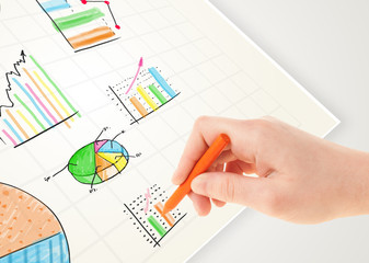 Business person drawing colorful graphs and icons on paper