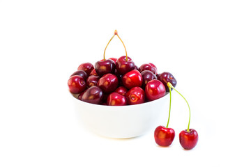 A white bowl of cherries isolated with a pair on front