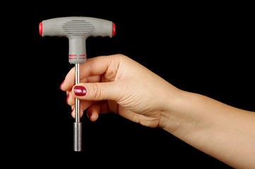 T wrench in female hand isolated on the black background