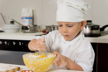Cute little chef mixing ingredients as he bakes