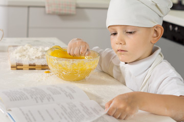 Little boy chef checking his recipe as he bakes