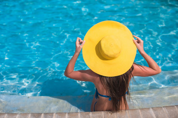 Fototapeta na wymiar Woman in yellow hat relaxing at swimming pool