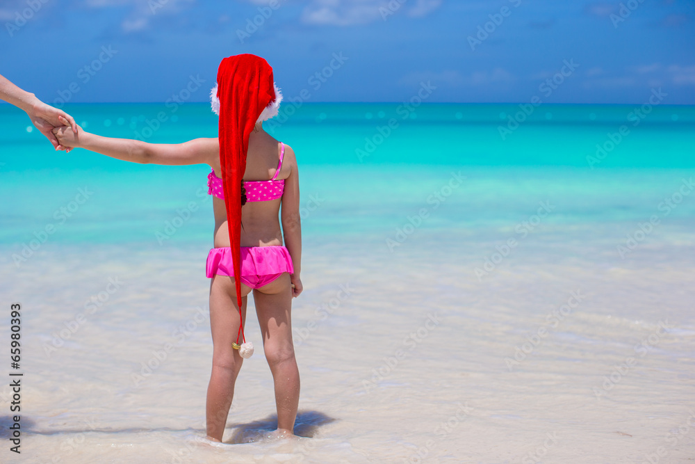 Wall mural Little adorable girl in red Santa Hat enjoy beach vacation