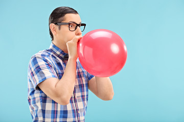 Man with glasses blowing up a balloon