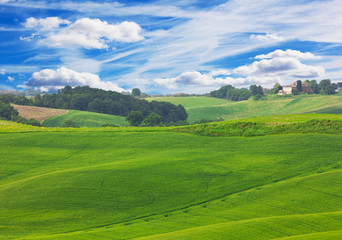 Obraz premium Green hills of Tuscany under blue sky with white clouds