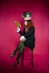 Fototapeta premium Young woman in the similitude of the Hatter reading book sitting